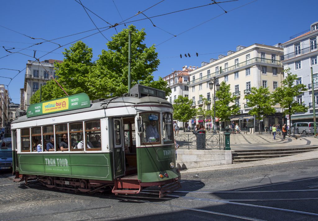 Spårvagn - grön linje, vid Torget Praça Luís de Camões. Ska den ta spåret till höger eller spåret till vänster? Vad pratar duvorna på tråden om?