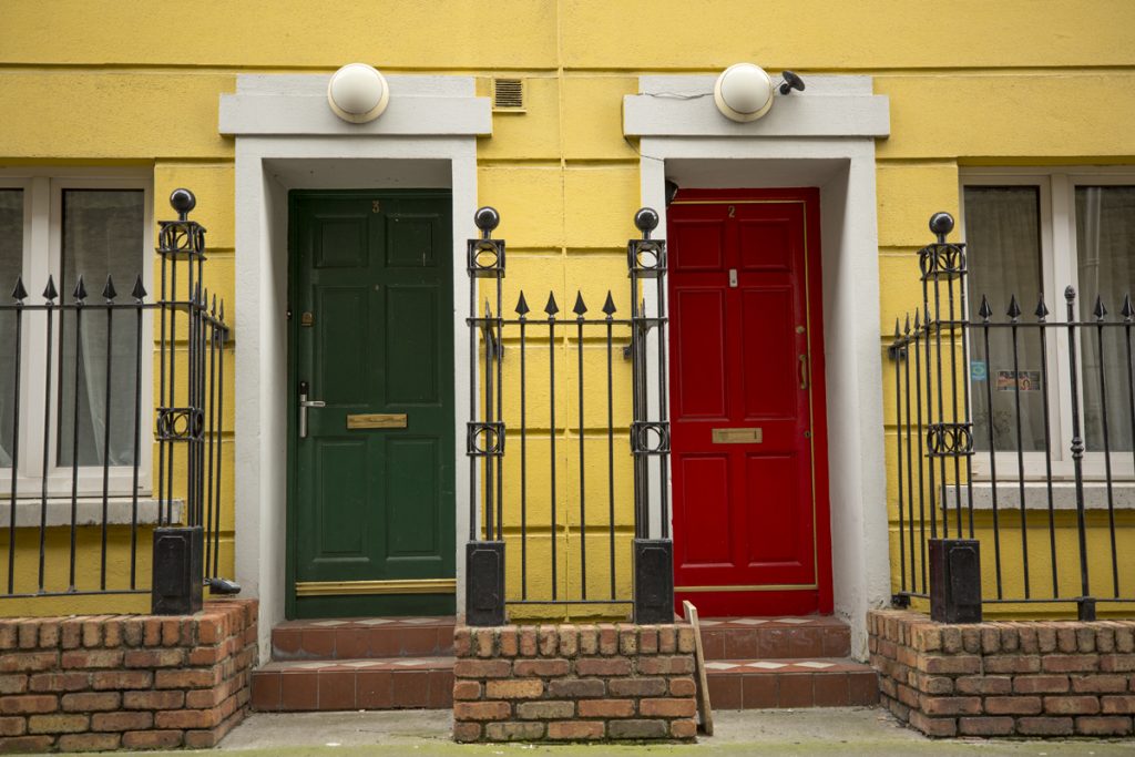 Två färglada dörrar på ett gult hus
